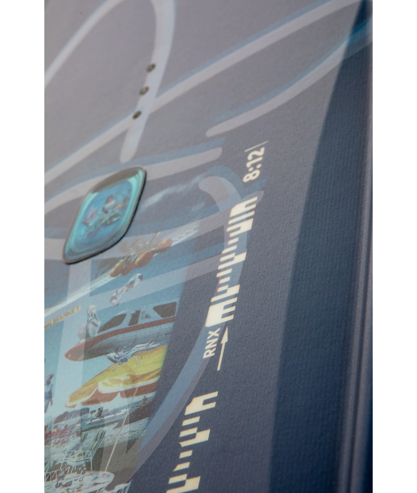 Ronix Supreme wakeboard graphic, top inset image of 8:12, showing the corner of the lenticular badge.