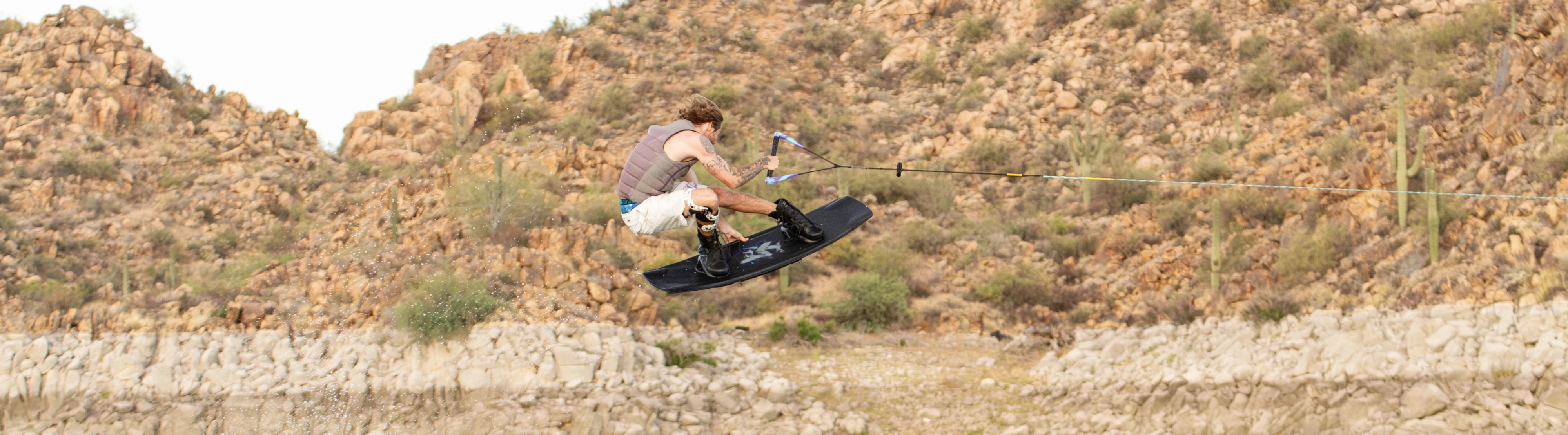 Action shot of Massi Piffaretti riding the Ronix RXT - Ronix Xperiemental Technology, with rocks in the background