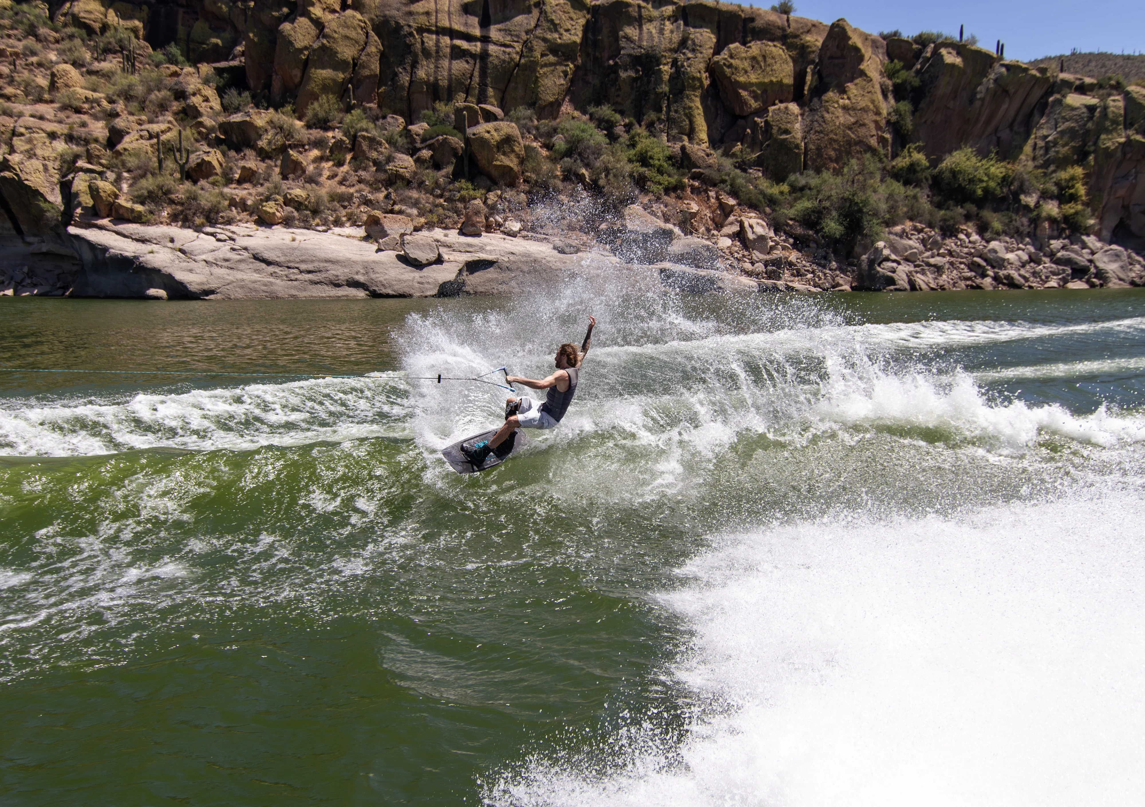 Action shot of Massi Piffaretti riding the Ronix RXT - Ronix Xperiemental Technology, with water and rocks in the background