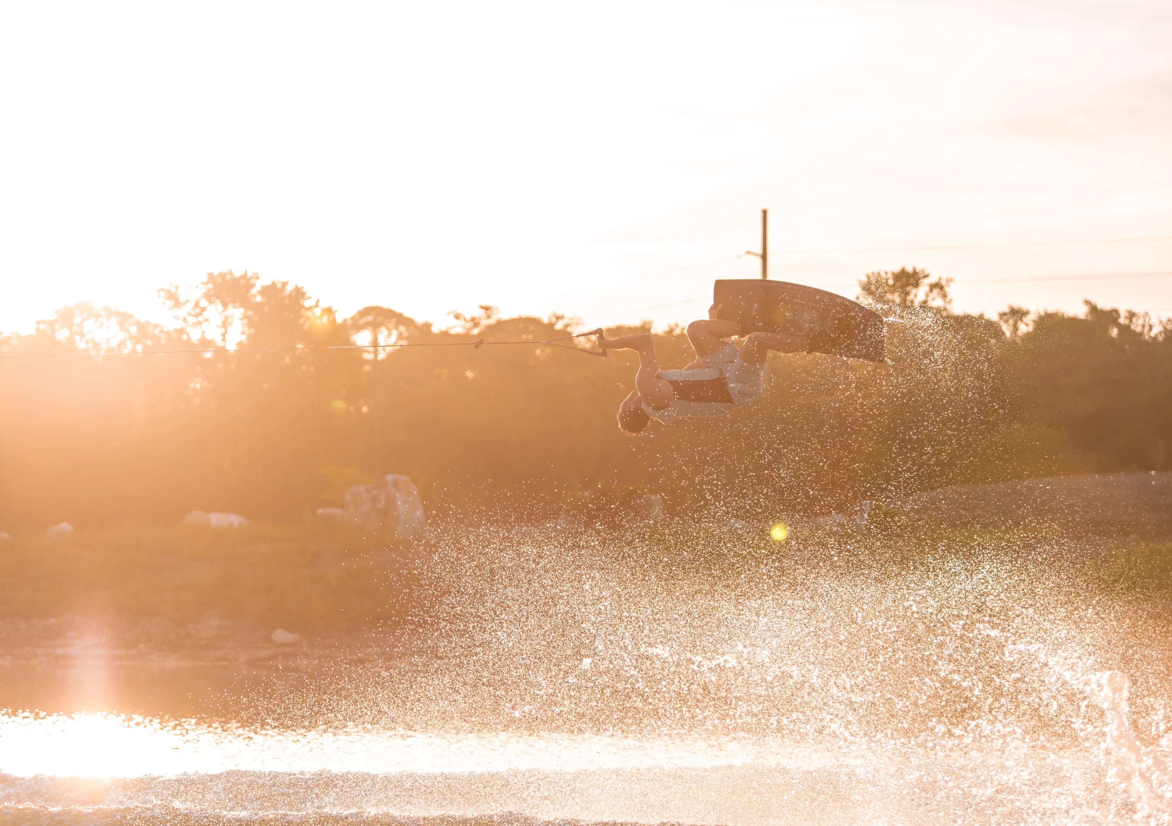 Action shot of Jake Pelot riding the Ronix Supreme wakeboard, sunrise shot with water spray everywhere